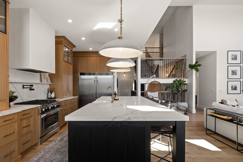 Kitchen open to a loft and staircase beyond, with pendant lighting over the island