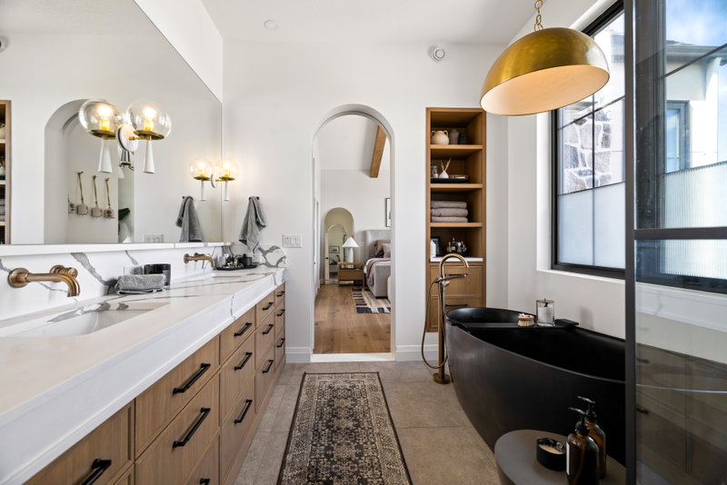 Ensuite with a walk-in glass shower, soaking tub and view to the bedroom
