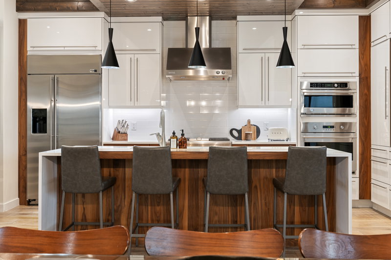 Kitchen island with counter stools beneath a wood-clad ceiling