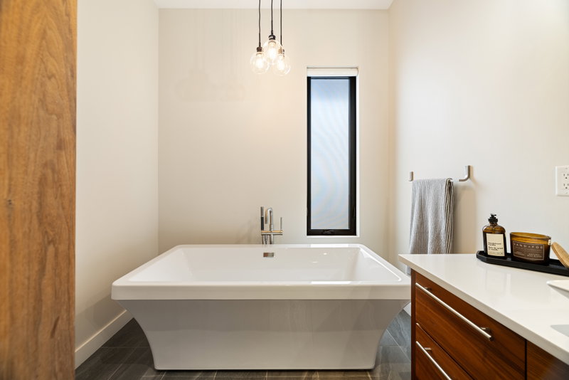 Ensuite with a freestanding soaker tub and walnut vanity