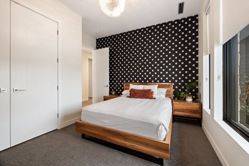 Guest bedroom with a polka-dot feature wall and walnut bed frame