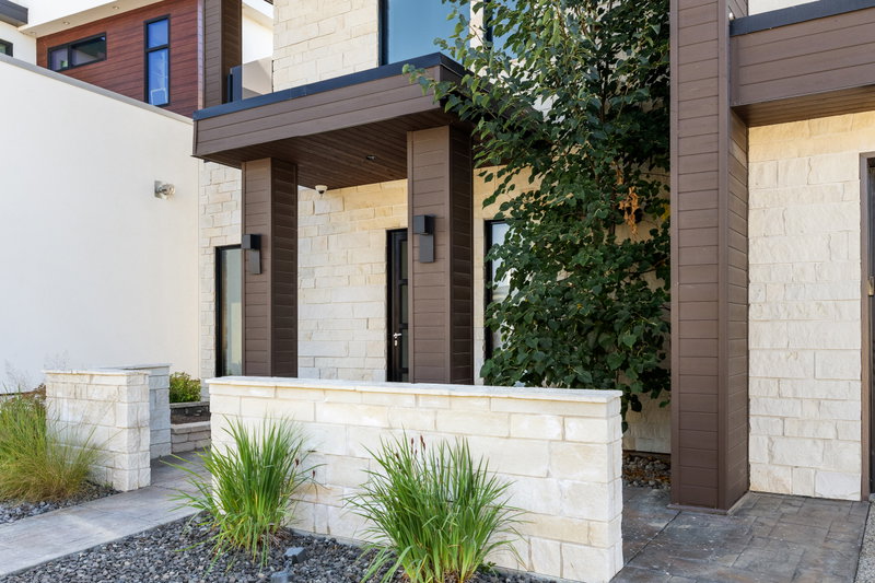 Front entry with an oversized pivot door and stone surround