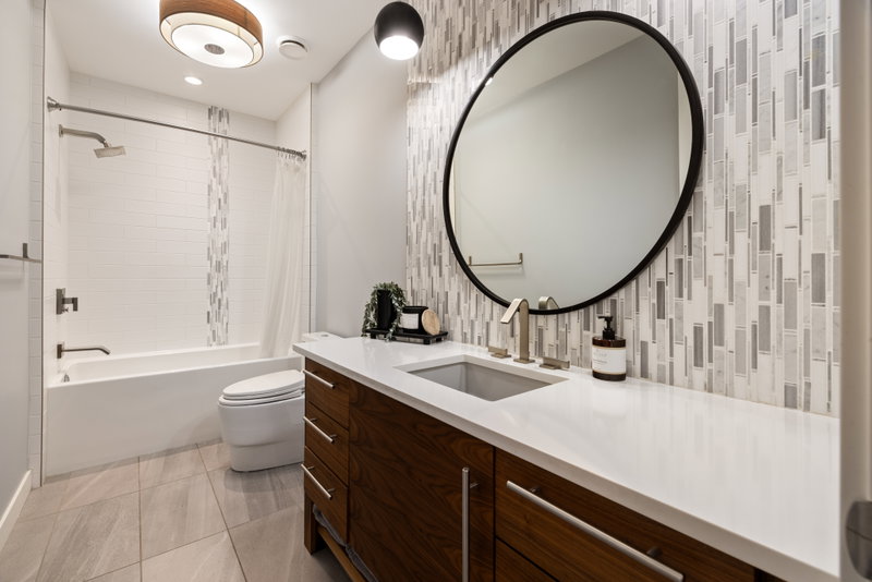 Upstairs bathroom with walnut vanity and glass-tile accent wall