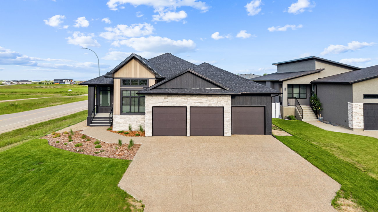 Modern bungalow exterior with stacked stone accents and a three-car garage