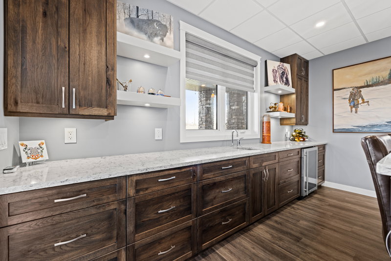 Basement wet bar with walnut cabinetry and a beverage fridge