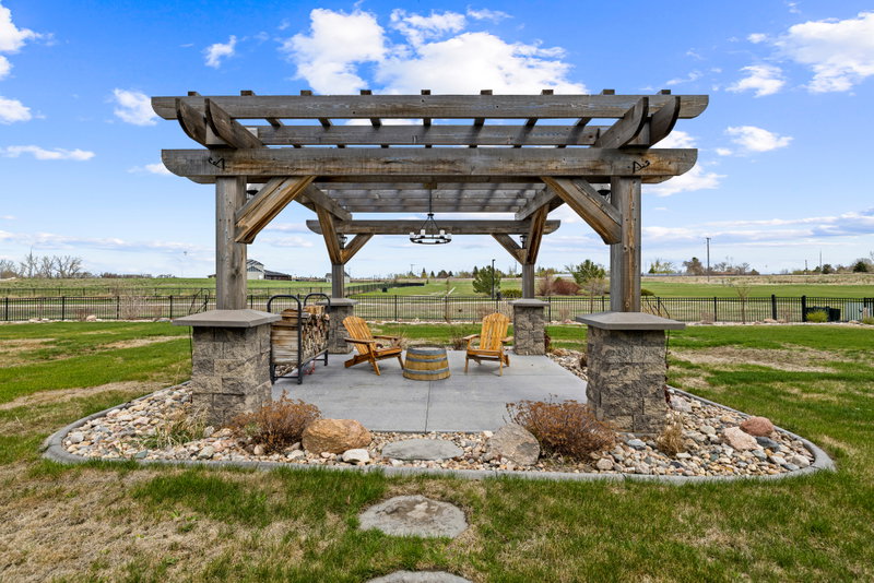 Backyard pergola with a fire pit and Adirondack chairs