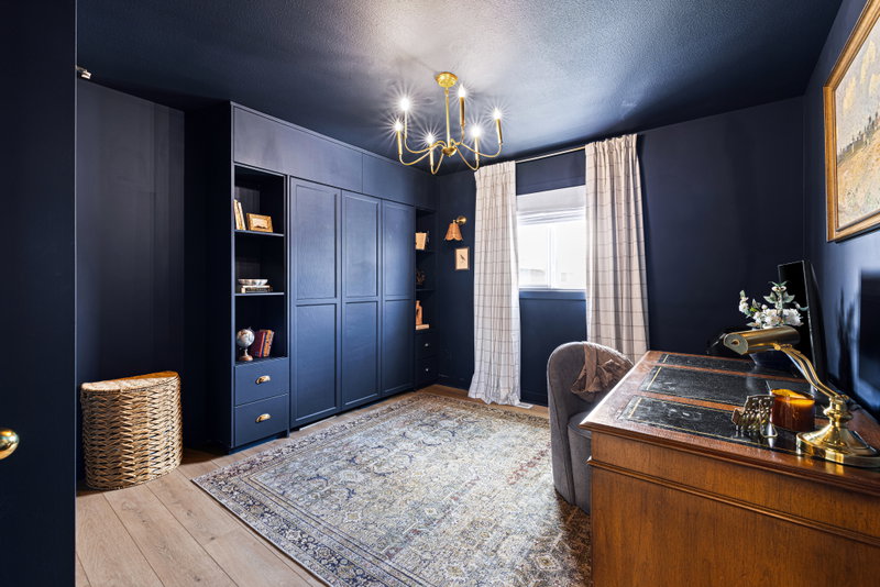 Navy-painted home office with built-in cabinetry and a vintage desk