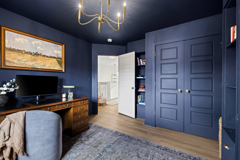 Navy-painted study with a leather-top desk and framed landscape art