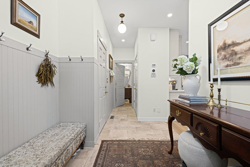 Entryway with wainscotting, wall hooks and a bench