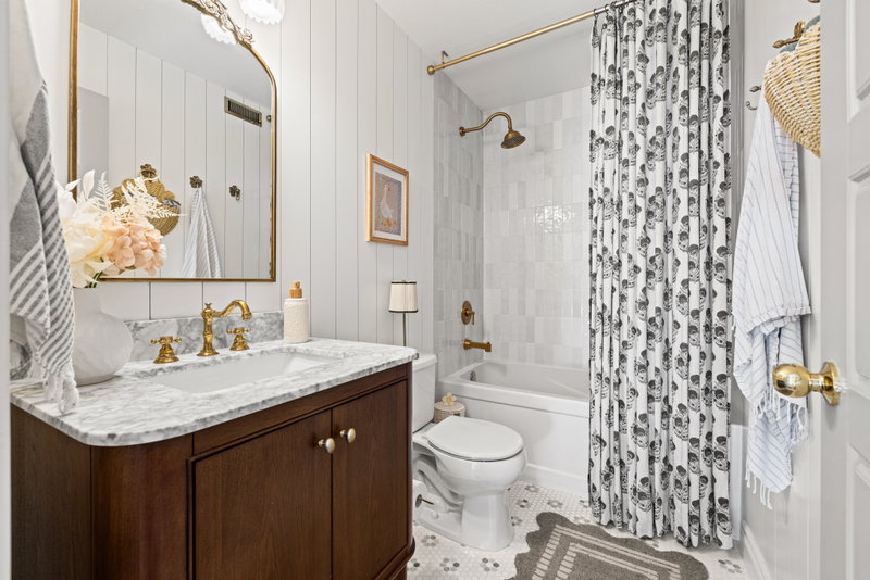 Main bathroom with a patterned shower curtain and brass fixtures