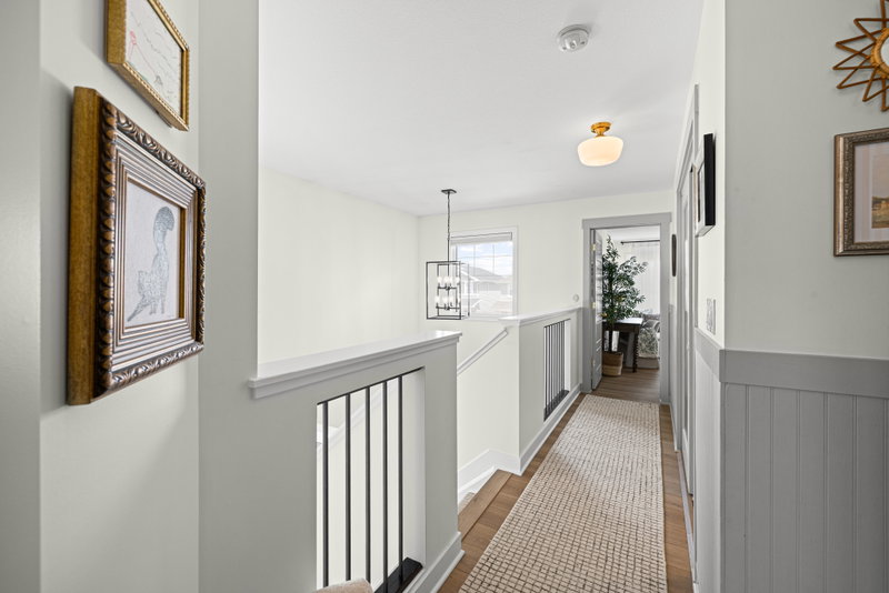 Upstairs hallway with a runner rug and pendant lighting