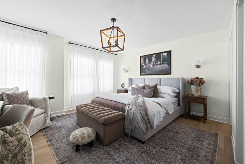 Primary bedroom with an upholstered headboard and cage-style chandelier