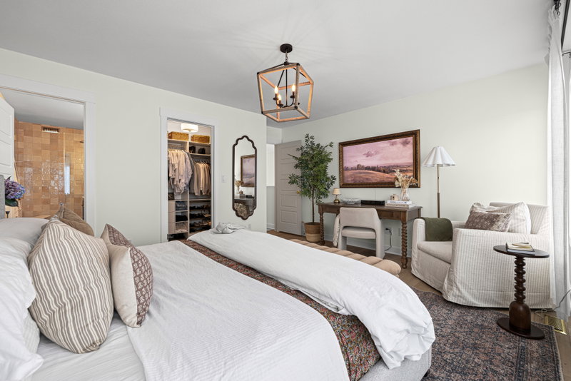 Primary bedroom with a walk-in closet and ensuite visible beyond