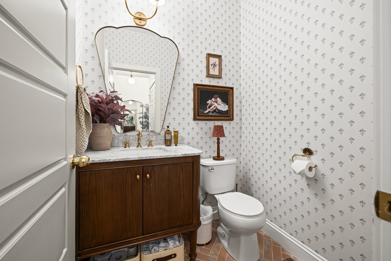Powder room with patterned wallpaper and a scalloped mirror