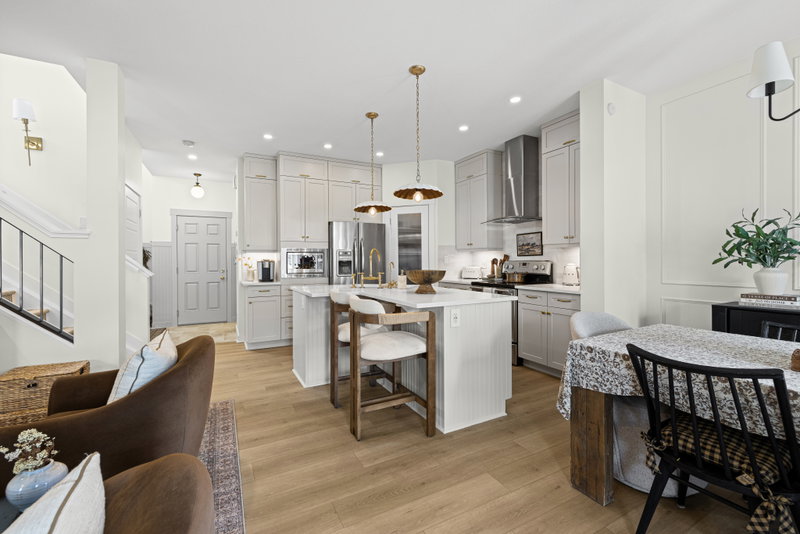Kitchen with light grey cabinetry, brass hardware and a scalloped pendant