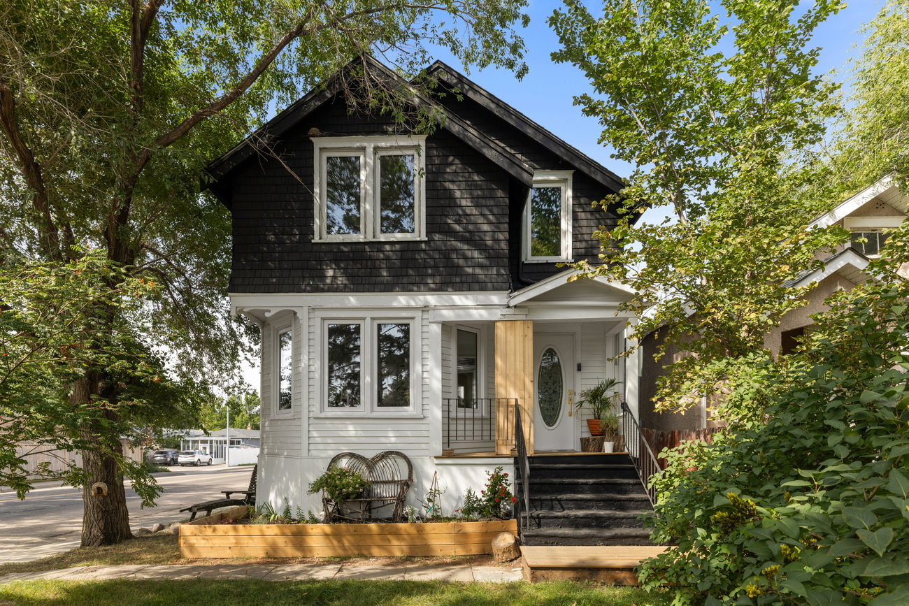 Character two-storey home with black shingle siding and a white porch