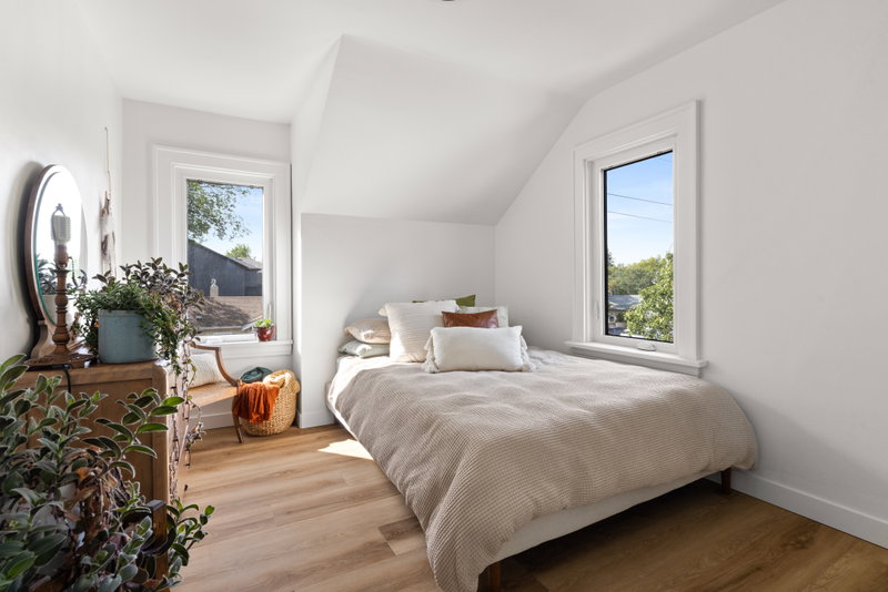 Bedroom beneath a sloped ceiling with an antique dresser and mirror
