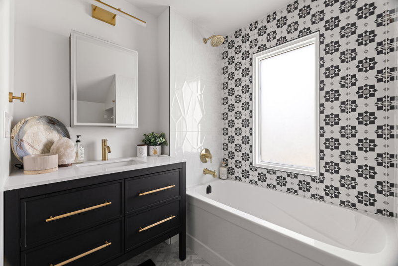 Bathroom with patterned black-and-white tile and a black vanity