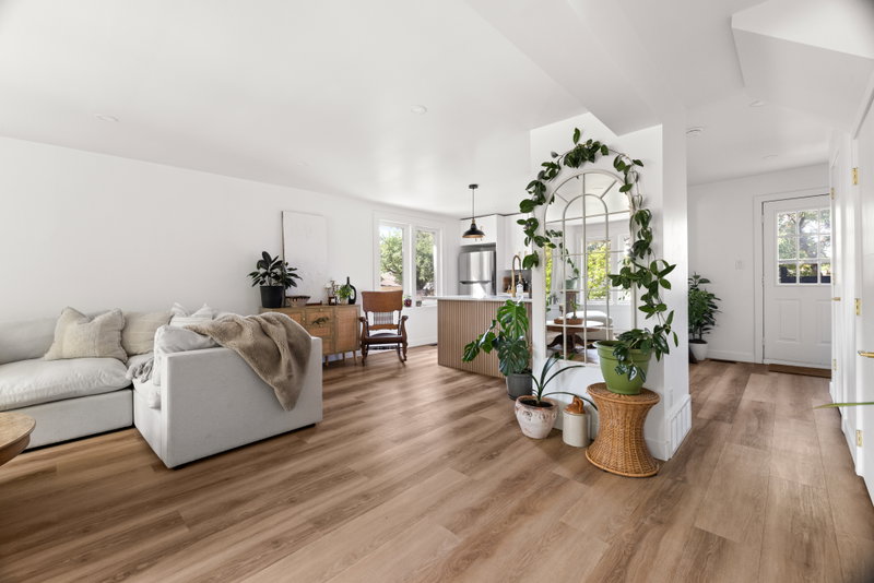 Open living area with an arched mirror, plants and the kitchen beyond