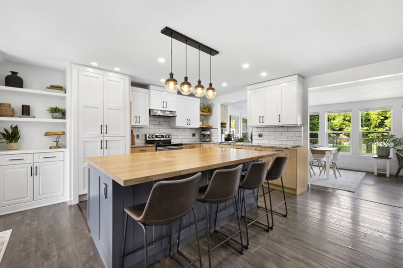 White kitchen with two chandeliers over the island and butcher-block counter