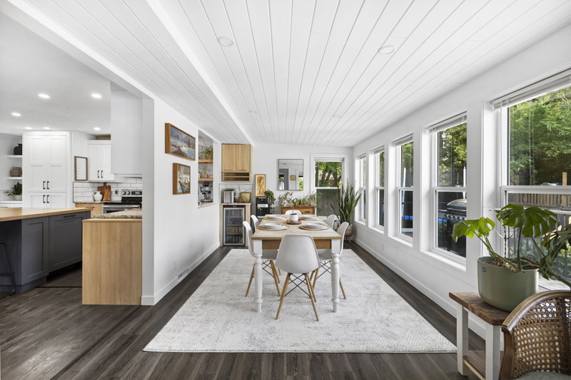 Sun room dining area with wall-to-wall windows overlooking the yard
