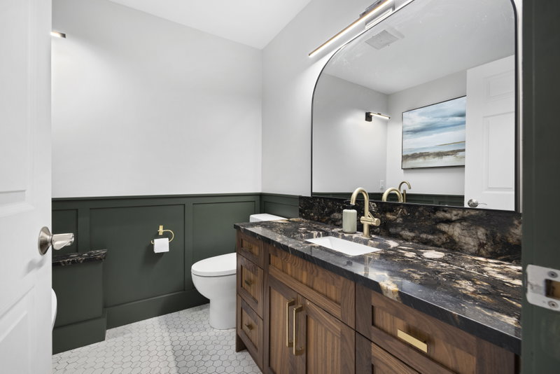 Bathroom with dark stone counter and curved arched mirror