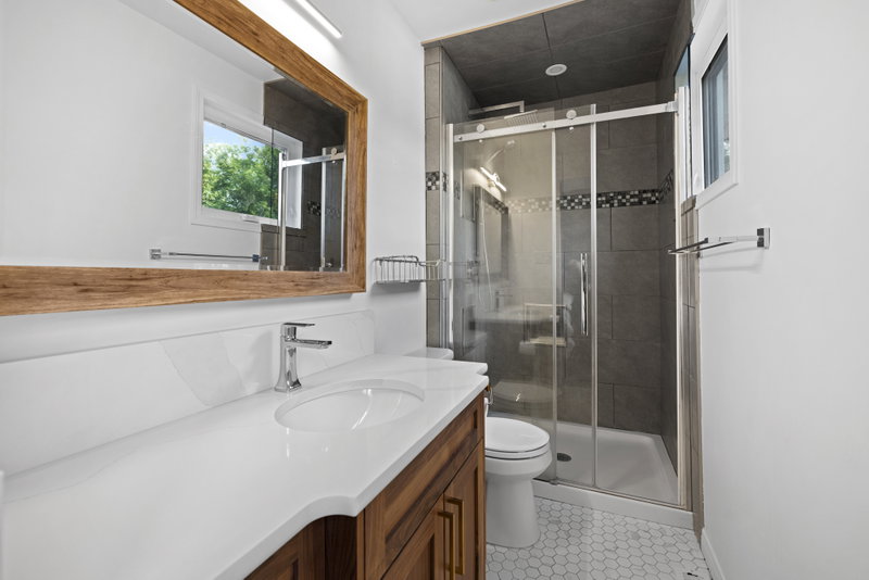 Ensuite bathroom with glass shower and wood-framed mirror