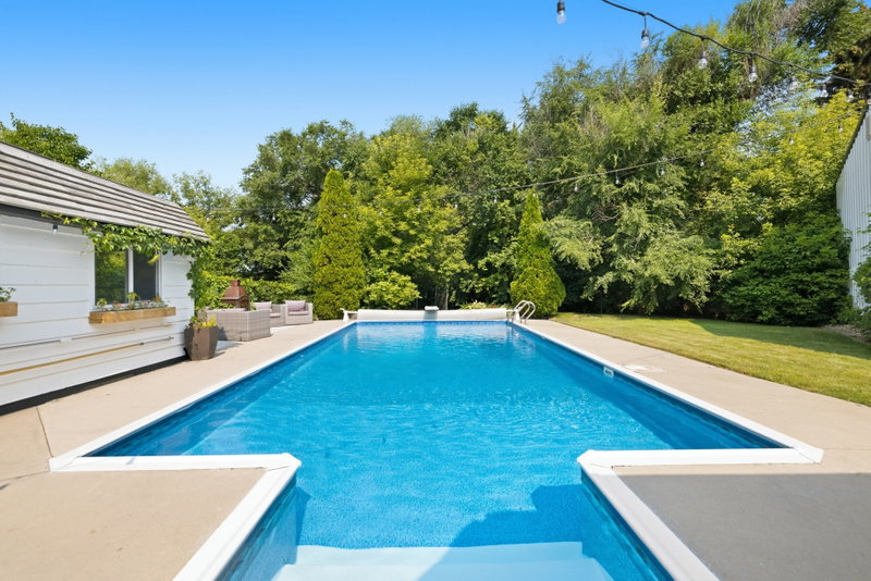 Pool with diving board and lounge seating by the cabana