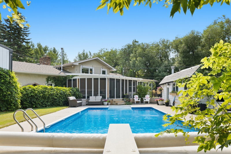 Pool and screened sun room addition, framed by mature trees