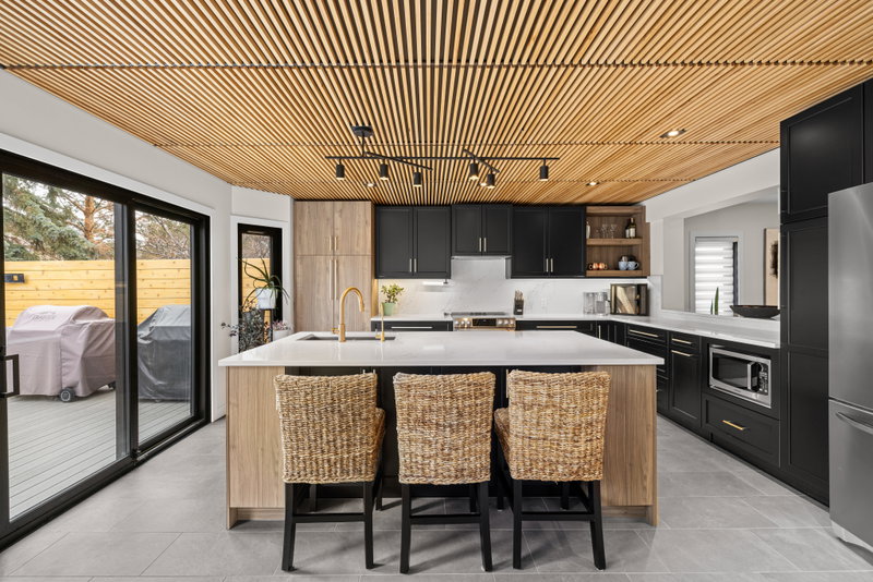 Kitchen island with woven counter stools beneath a slatted wood ceiling