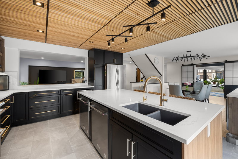 Island sink with gold faucet and a built-in television nook beyond