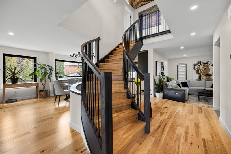 Curved open staircase with dark wood treads and black railing