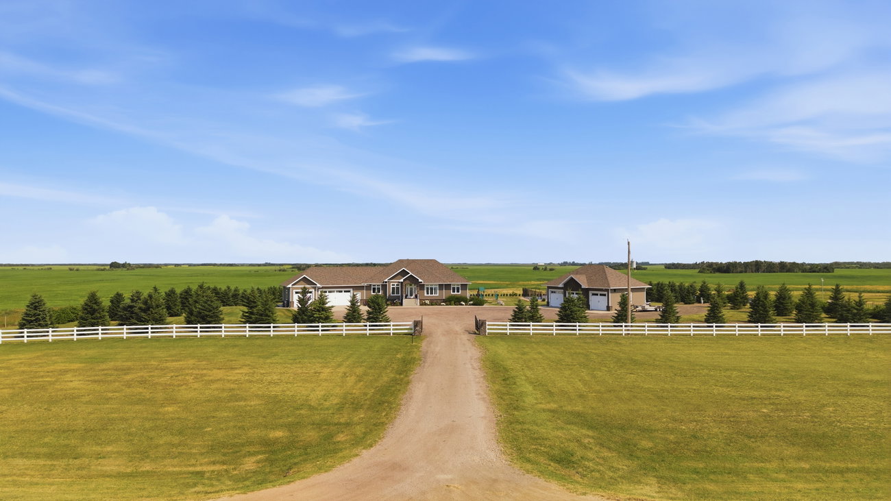 Aerial photograph of an acreage property with a long gravel driveway through open fields