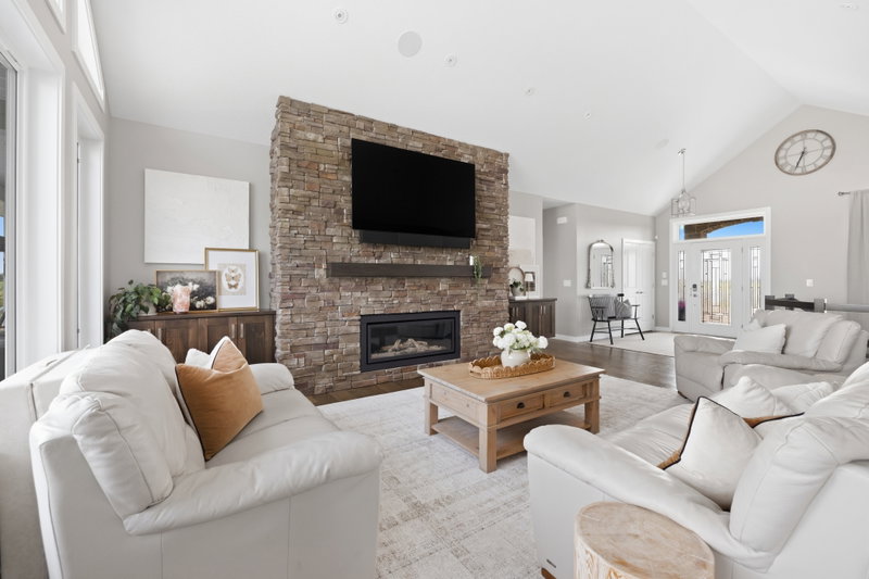 Living room with a stone fireplace, open to the front entry and hallway