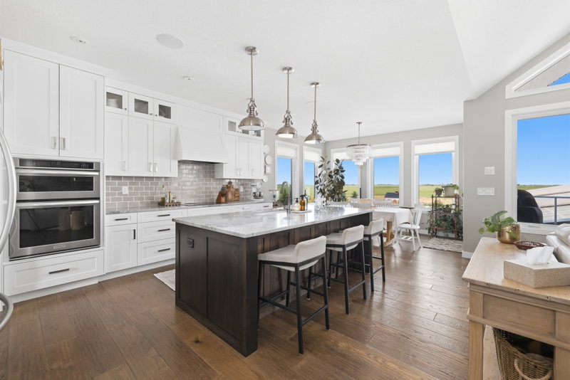 Kitchen with a long run of white cabinetry, open to the dining and living areas