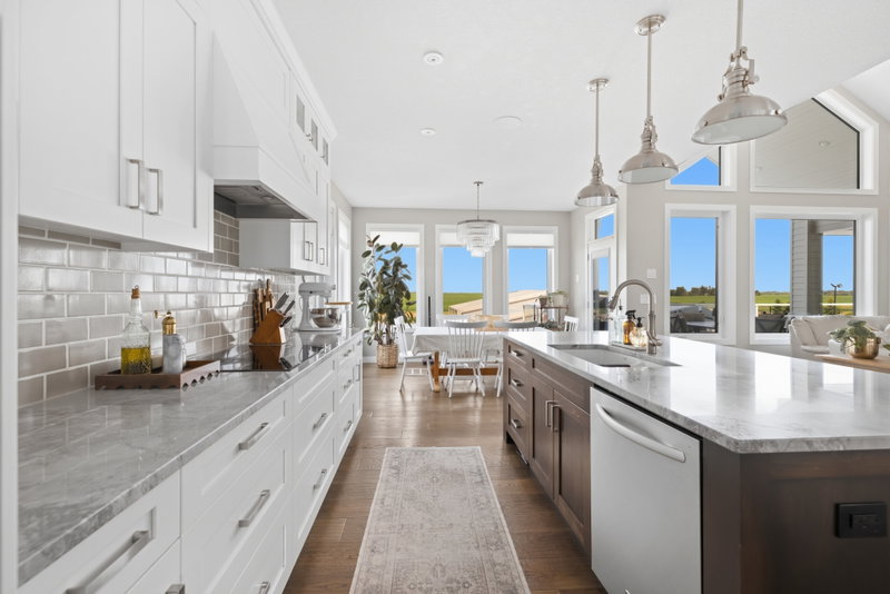 Kitchen with subway tile backsplash, open to the dining table and windows beyond