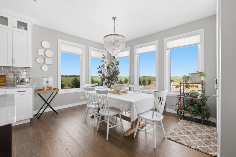 Dining area beneath a chandelier, framed by floor-to-ceiling windows overlooking the fields