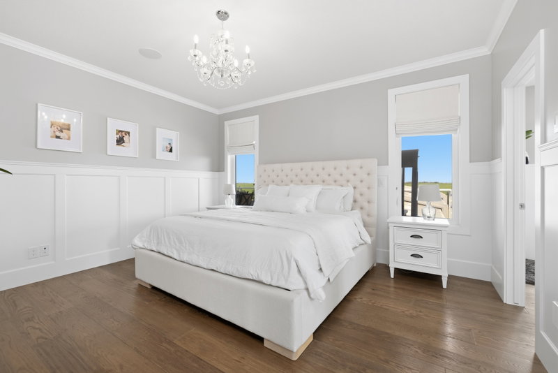Primary bedroom with a tufted upholstered headboard and wainscotting